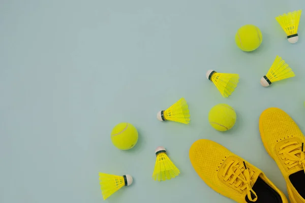 Yellow snickers, shuttlecocks and tennis balls on a blue background with copy space