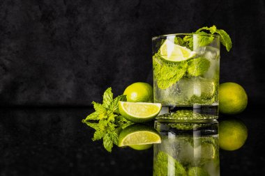 Limonlu mojito ve naneli, yansımalı bardağın yanında.