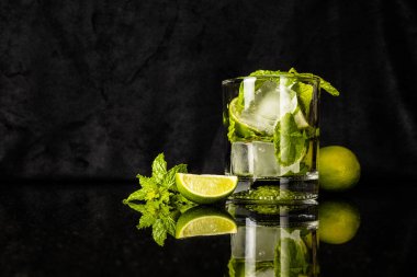Limonlu mojito ve naneli, yansımalı bardağın yanında.