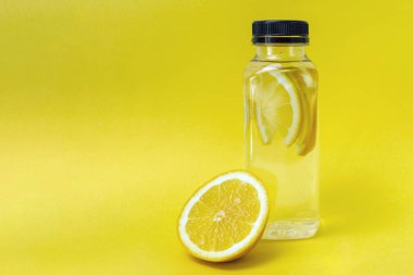 Sarı zemin üzerinde limon dilimleri olan bir şişe su ve fotokopi alanı