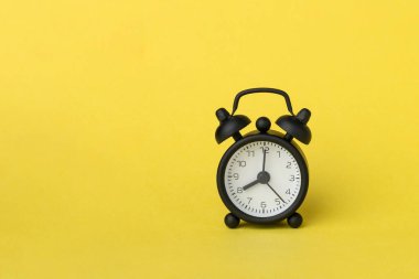 Saat 8 yönünde sarı arka planda küçük bir çalar saat var.