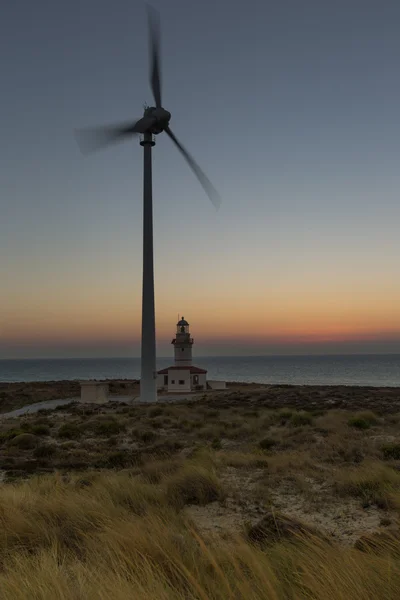 Wind turbines generating clean power with lighthouse — Stock Photo, Image