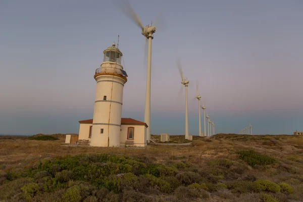 Wind turbines generating clean power with lighthouse — Stock Photo, Image