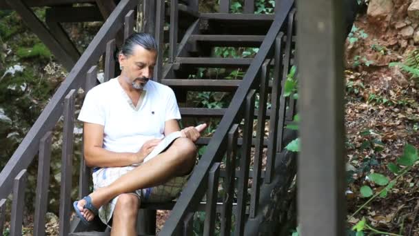 Мужчина среднего возраста брюнетка читает книгу — стоковое видео