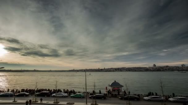 Time Lapse Fotografía personas caminando por la costa con la Torre de la Doncella al atardecer — Vídeos de Stock