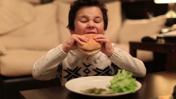 Schattige jongen beet heerlijk hamburger — Stockvideo