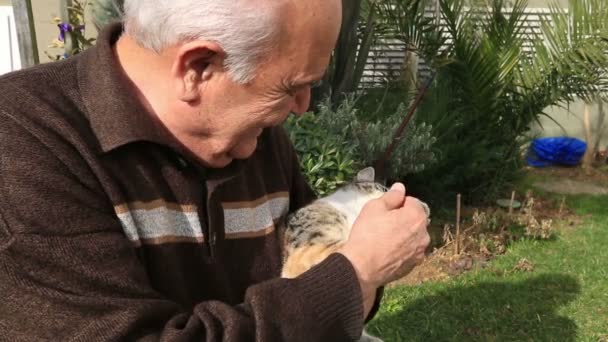 Äldre man spela en katt i trädgården — Stockvideo