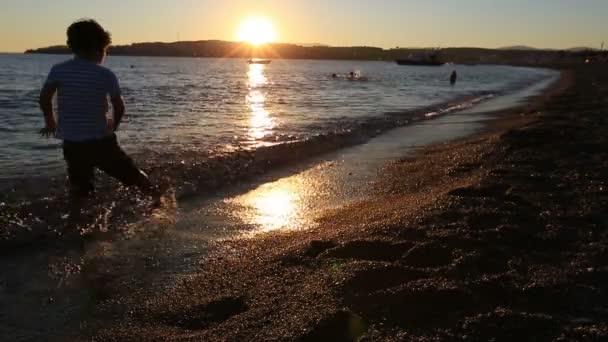 Niño disfrutando en la playa al atardecer — Vídeos de Stock