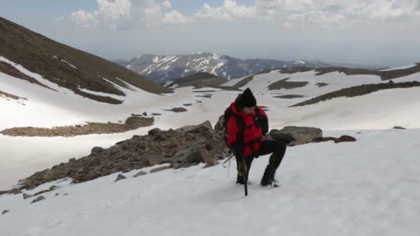 Hombre subiendo a la montaña nevada — Vídeo de stock