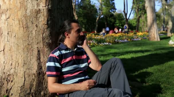 Άνθρωπος μιλώντας στο κινητό τηλέφωνο στο πάρκο — Αρχείο Βίντεο