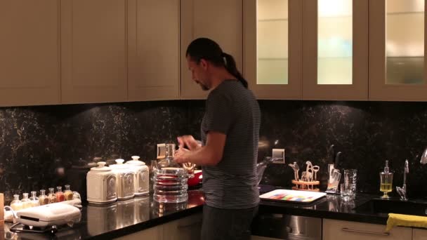 Hombre sediento bebiendo un vaso de agua en la cocina de lujo — Vídeos de Stock