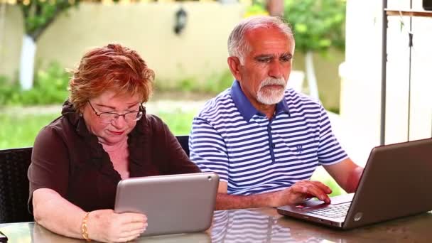 Pareja de personas mayores utilizando ordenador portátil y tableta digital — Vídeo de stock