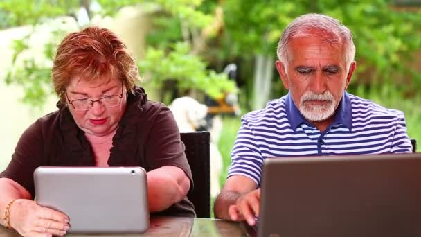 Senior paar met behulp van de laptop en digitale tablet — Stockvideo