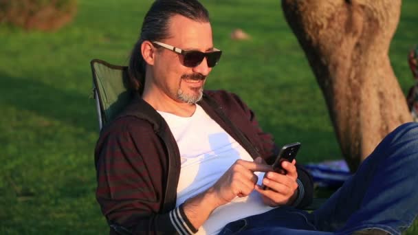 Hombre usando teléfono inteligente en el parque de la ciudad — Vídeos de Stock