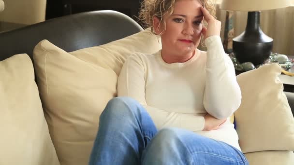 Portrait of a sad worried woman sitting on a sofa — Stock Video