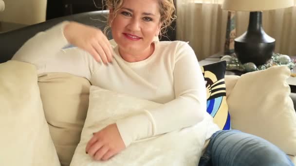 Porträtt av en leende kvinna som sitter på en soffa — Stockvideo