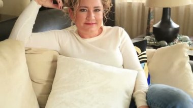Kanepede oturan ve kameraya gülümseyen kadın