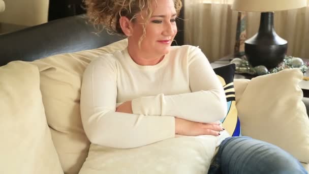 Woman sitting on a sofa and smiling to camera — Stock Video