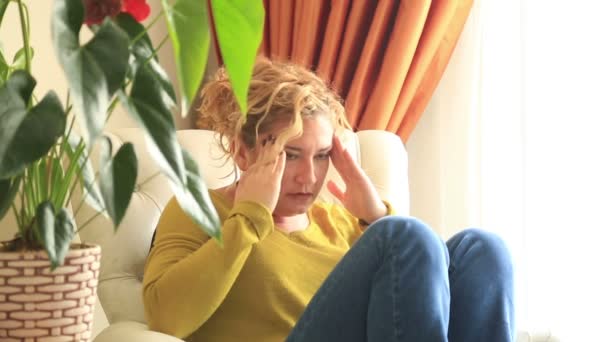 Fájdalmas nő a kanapéra, a fejfájás és a kezét a homlokára — Stock videók