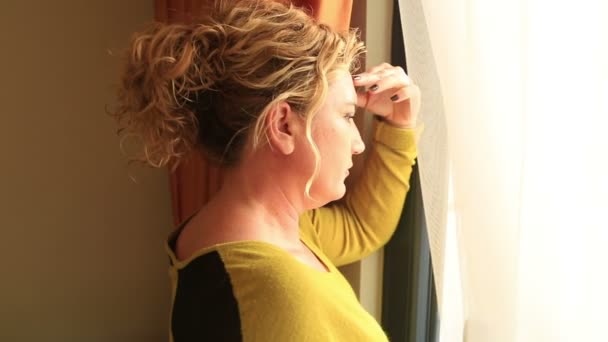 Λυπημένη γυναίκα στέκεται δίπλα στο και κοιτάζοντας έξω από το παράθυρο — Αρχείο Βίντεο