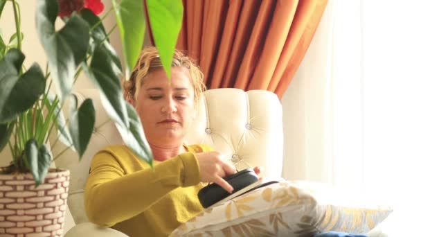 Woman putting on glasses and reading a book — Stock Video