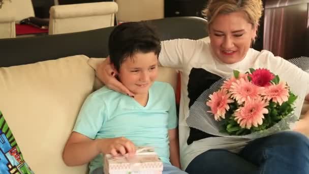 Lindo chico ofreciendo regalo a su madre en la sala de estar — Vídeos de Stock