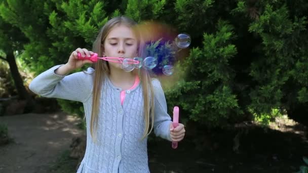 Menina brincando com bolhas de sabão em um fundo ambiente verde — Vídeo de Stock