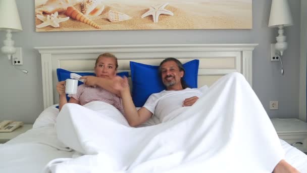 Pareja acostada en una cama viendo televisión juntos — Vídeo de stock