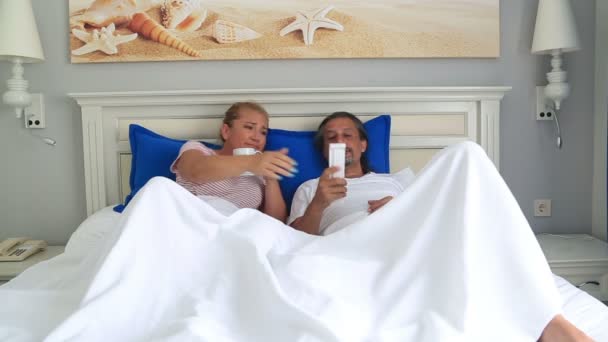 Пара, лежащая на кровати и смотрящая телевизор вместе — стоковое видео