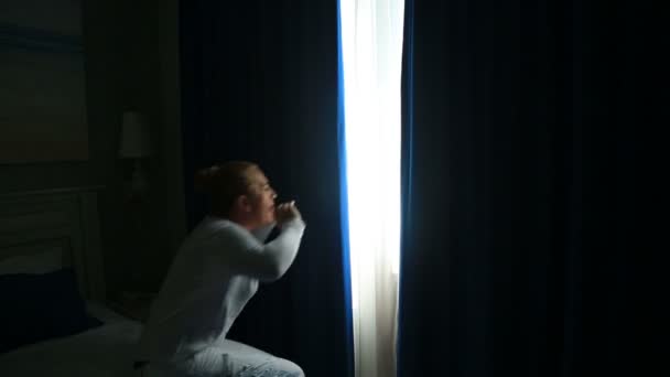 Жінка прокидається і відкриває штори — стокове відео
