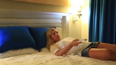 Uyku hali, yorgun kadın Tv uzaktan kumanda ile bir yatakta yatarken