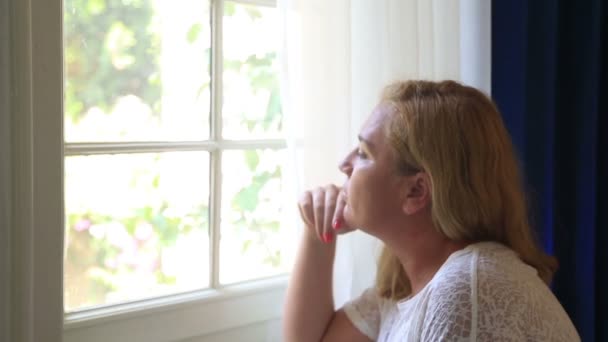 Женщина смотрит в окно — стоковое видео
