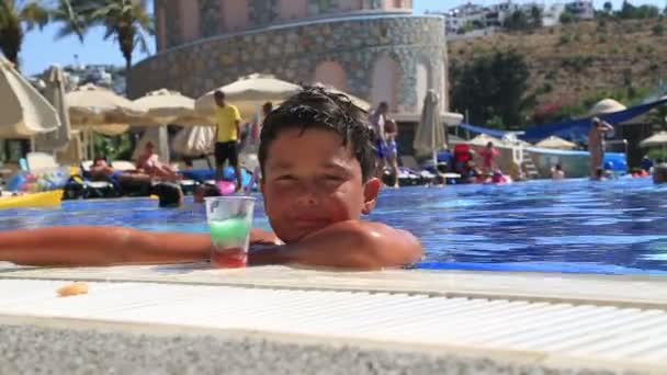 Niño bebiendo jugo de bebidas de verano en la piscina — Vídeos de Stock