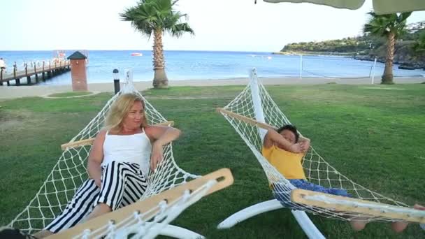 Mother and son relaxing in a hammock near the sea — Stock Video