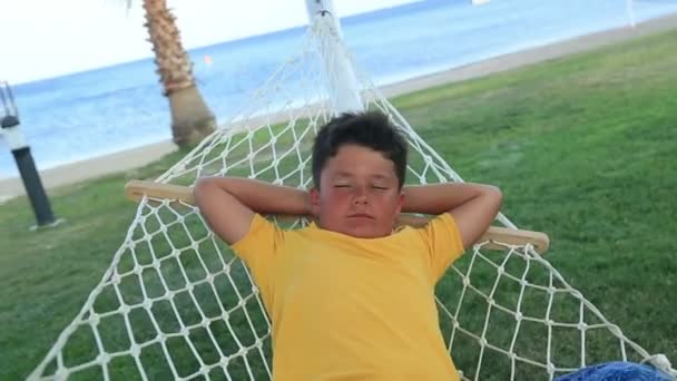 Fiatal fiú pihentető egy függőágyban, a tenger közelében — Stock videók