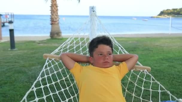 Young boy  relaxing in a hammock near the sea — Stock Video