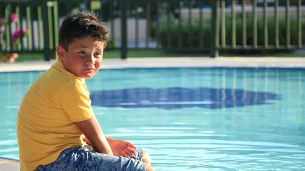 Мальчик сидит у бассейна — стоковое видео