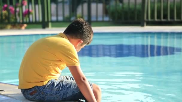 Bambino felice in vacanza estiva seduto vicino alla piscina — Video Stock