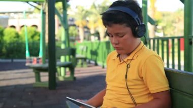 Parkta dijital tablet kullanarak kulaklık ile genç çocuk