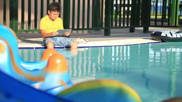 Jeune garçon utilisant une tablette numérique près de la piscine — Video