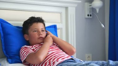 Bir yatakta yatarken ve akıllı telefon kullanarak çocuk 