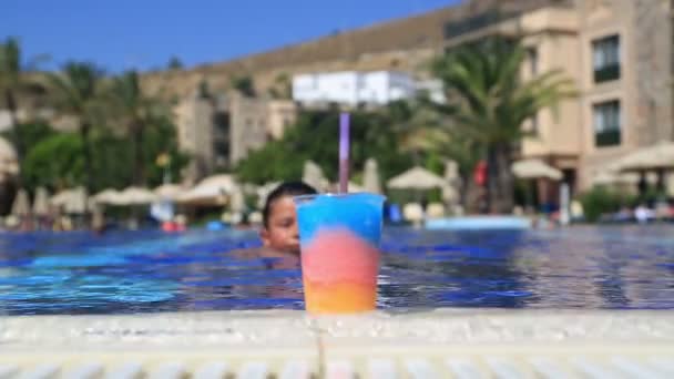 Niño feliz bebiendo bebida de verano en una piscina — Vídeos de Stock