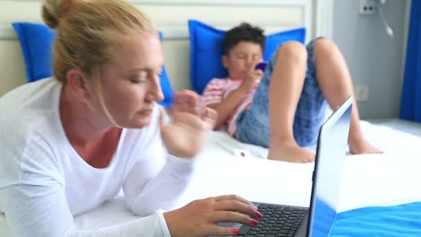 Madre e figlio sdraiati su un letto e utilizzando attrezzature digitali — Video Stock