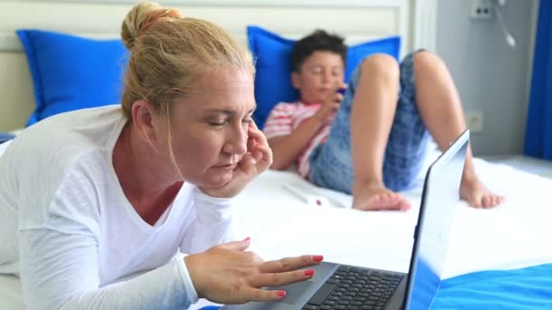 Madre e figlio sdraiati su un letto e utilizzando attrezzature digitali — Video Stock