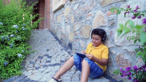 Kleiner Junge mit Kopfhörer mit digitalem Tablet 2 — Stockvideo
