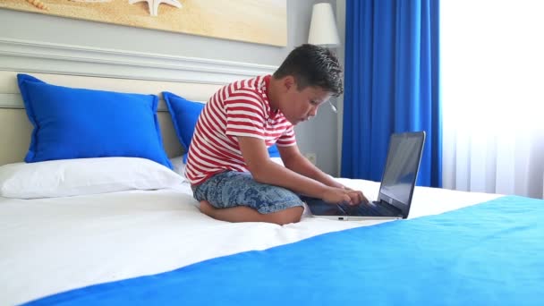 Παιδί ξαπλωμένο σε ένα κρεβάτι και χρησιμοποιώντας φορητό υπολογιστή — Αρχείο Βίντεο