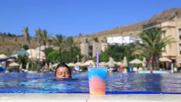 Criança feliz bebendo bebida de verão em uma piscina — Vídeo de Stock