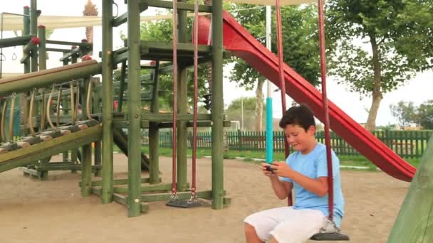 Enfant relaxant avec smartphone dans l'aire de jeux 4 — Video