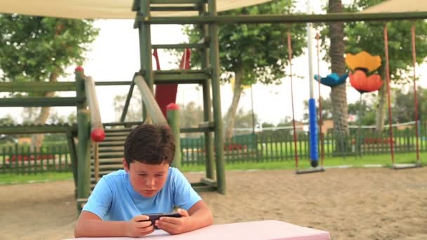 Bambino relax con smartphone nel parco giochi — Video Stock