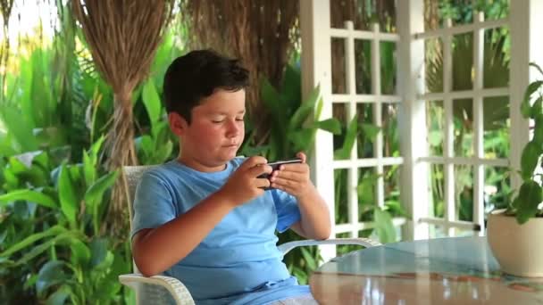 Child relaxing with smartphone in summer cafe 3 — Stock Video